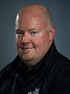 bio_michael-baxter Here's an alt tag for the image: Headshot of a man in a dark shirt.